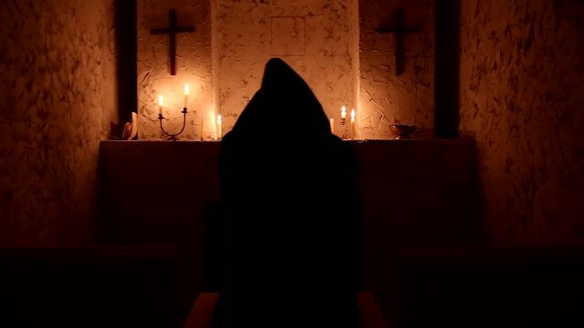 The monk walks the dark room to the altar