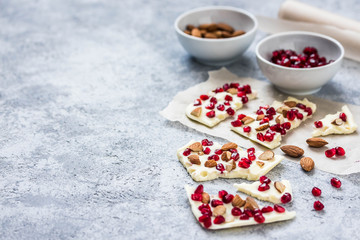 Healthy coconut oil chocolate pomegranate nuts bites on concrete background. Selective focus, space for text. 