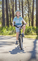 Obraz premium Active, Healthy Boy riding his bike on a sunny day on a bike path outdoors. Smiling and enjoying nature on a sunny warm day. Exercising and being active during the summer