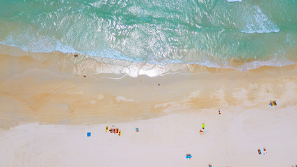 Aerial : Overhead  of people enjoying the summer at sand  beach ,waves breaking against the coast line
