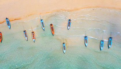 Aerial: Shoreline with fishing boats and long tail taxi boats parking along the sand beach in Thailand