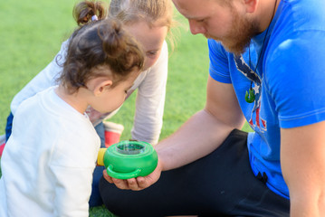 The father shows the caterpillar to the kids.Bearded dad with children in summer garden. Man  teacher with children in nature class. A lesson about insects.