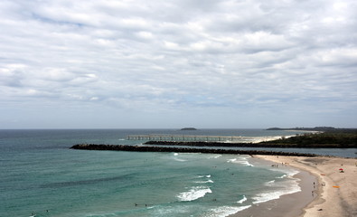 Fototapeta na wymiar Duranbah beach and breakwall at the entrance of Tweed River on a cloudy day. Duranbah Beach, officially known as Flagstaff beach is the most northern beach in New South Wales.