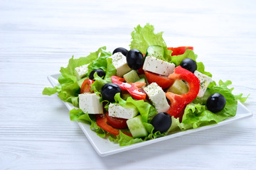 Greek salad on a white wooden background. Space for text or design.