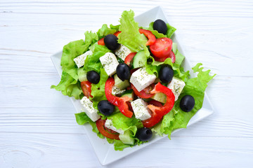 Greek salad on a white wooden background. Space for text or design.