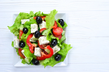 Greek salad on a white wooden background. Space for text or design.