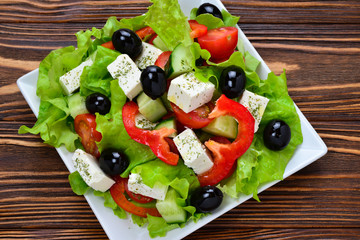 Greek salad on a wooden background. Space for text or design.