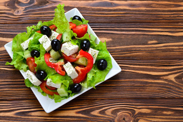 Greek salad on a wooden background. Space for text or design.