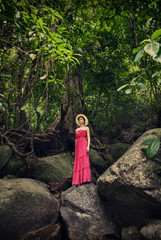 A girl in the jungle is standing on a rock. Waterfall in the jungle.