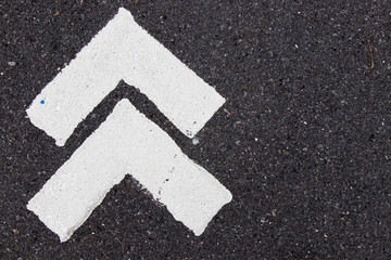 White painting in forward direction arrow symbol on black asphalt road background