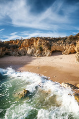 Beautiful coast of the ocean, Algarve, Portugal. Waves break against the rocks in the sun