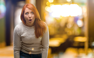Beautiful young redhead woman scared in shock, expressing panic and fear at night