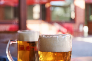 Two glasses of beer standing on a table in a garden pub on a summer sunny day