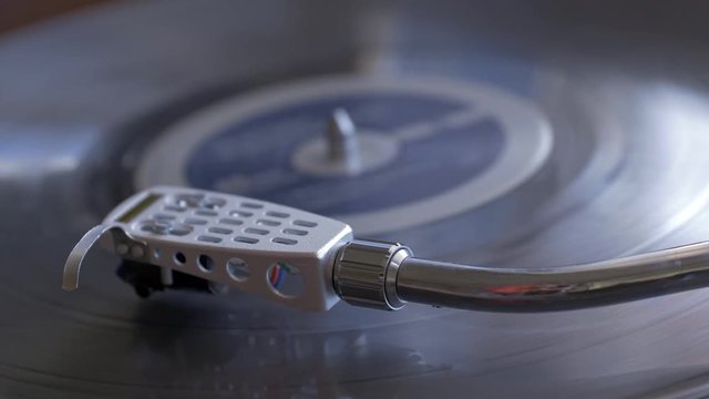 Panning shot of turntable tone arm as music plays