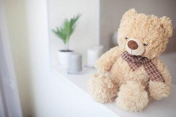 Soft toy bear in a bright bedroom.