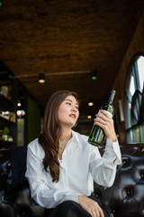 business woman is sitting in restaurant and very drunk, her left hand holding bottle of wine.