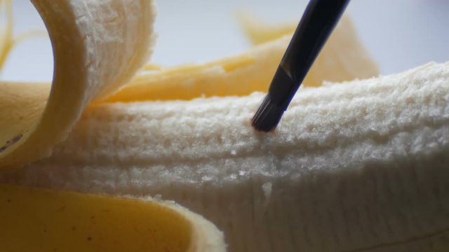 Woman sexually caresses with a brush of purified banana, macro close up view