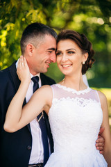 Young couple, bride and groom walking and enjoying their wedding day. Sunshine. Summer