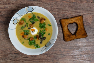 homemade cream broccoli soup. wooden background, croutons, blue cheese and hearts of toasted bread for decoration.Top view