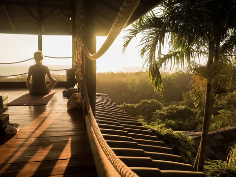 tropical open yoga studio place with people and a view outside to the ocean while sunset