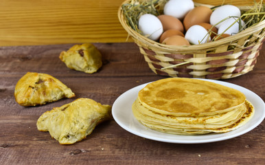 On the table, pancakes and hot pastries, eggs in a basket
