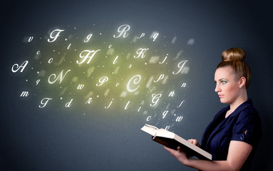 Casual young woman holding book with shiny letters flying out of it