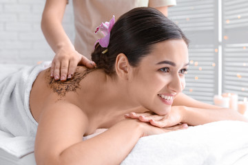 Obraz na płótnie Canvas Young woman having body scrubbing procedure in spa salon