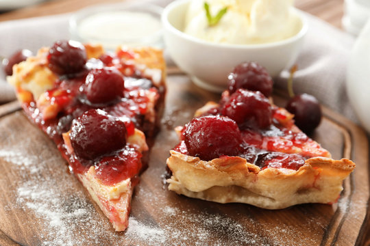 Delicious pieces of cherry pie on wooden board