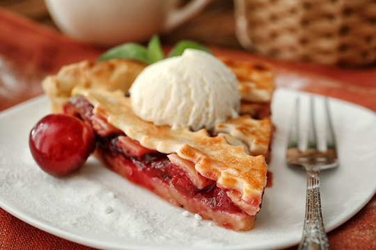 Delicious piece of cherry pie with ice cream on plate, closeup