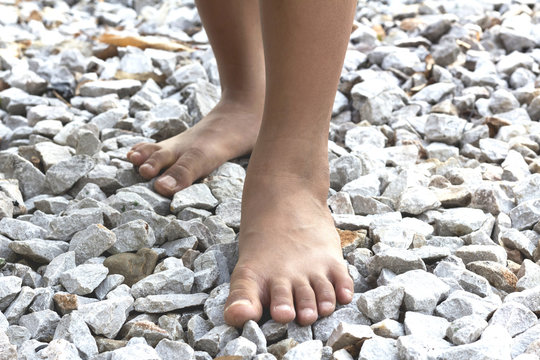 Closeup of a girl bare feet walking on stones rock