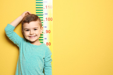 Little boy measuring his height on color background - obrazy, fototapety, plakaty