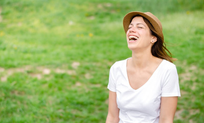 Fototapeta premium Happy brunette girl with hat laughing hard in the nature