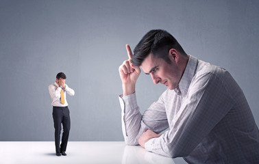 Young professional businessman being angry with an other miniature businessman 