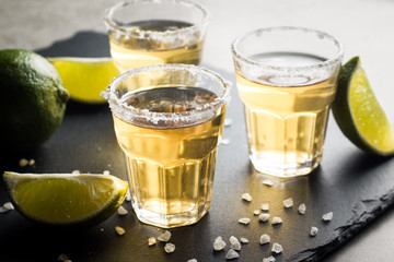Macro photo of shots of gold Mexican tequila with lime and salt on wooden rustic background....