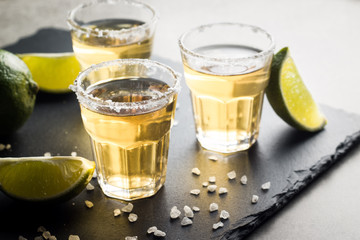 Macro photo of shots of gold Mexican tequila with lime and salt on wooden rustic background. Alcoholic drink concept. selective focus.
