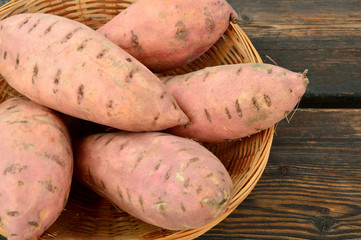 Health Benefits of Sweet Potatoes or Yams.
A lot of Sweet Potatoes in basket on wooden background