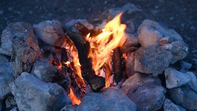 Bonfire in a camp-fire of stones outdoors at dusk