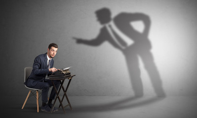 Little man working and a big shadow arguing with him
