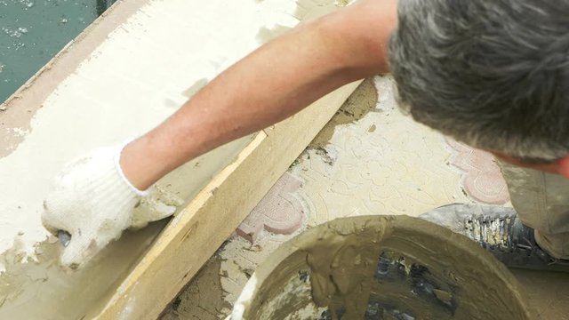 spatula and bucket with mortar on the construction site. the builder finishes the surface with plaster. 4k. pool repair.