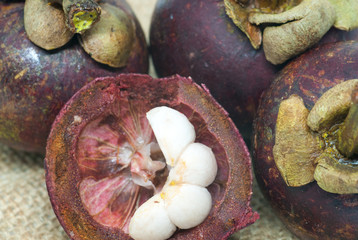 ripe delicious mangosteen whole fruits and sliced on patch of hemp bag close up photo