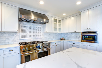 White Kitchen with stainless steel hood over gas cooktop.