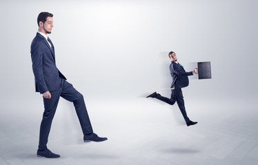 Small young man fired by his bos from his workplace with suitcase on his hand
