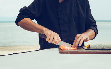 Chef cutting salmon for sushi roll