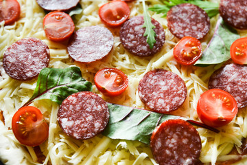 Ingredients for Pizza: basis dough, salami sausage, cherry tomatoes, grated cheese, tomato paste, herbs and arugula. Natural Wooden Background With Linen Napkin and Knife For Pizza