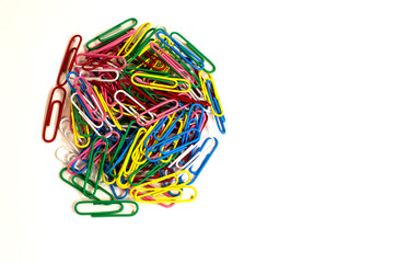 stationery paper clips of different colors pile lying on white background