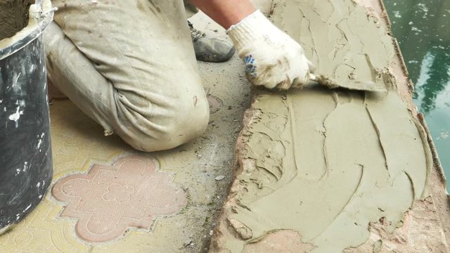 spatula and bucket with mortar on the construction site. the builder finishes the surface with plaster. 4k. pool repair.