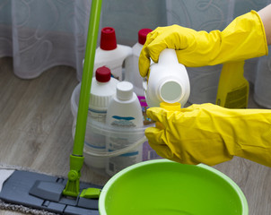 a girl in yellow gloves pours a cleanser in a green bucket, close-up