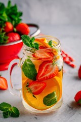 Infused detox water with orange, strawberry and mint. Ice cold summer cocktail or lemonade.