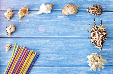 Sea shells and drinking straws on a blue wooden background