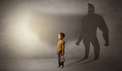 Cute kid in a room with plush on his hand and hero shadow on his background
